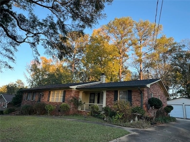 Single story home featuring a porch, a garage, a front lawn, and an outdoor structure