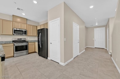 Kitchen featuring stainless steel appliances, light stone countertops, light brown cabinets, light tile patterned floors, and recessed lighting