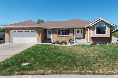 Ranch-style home with a front lawn, brick siding, concrete driveway, and an attached garage