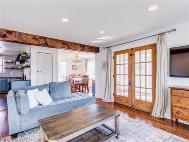 Living room featuring a textured ceiling, beamed ceiling, a notable chandelier, french doors, and dark hardwood / wood-style flooring