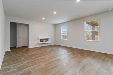 Unfurnished living room featuring recessed lighting, a warm lit fireplace, and light wood-style flooring