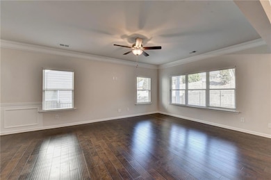 Empty room featuring ornamental molding, dark wood