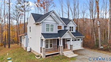 View of front of house featuring covered porch, roof with shingles, gravel driveway, and a view of trees