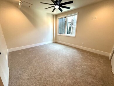 Carpeted spare room featuring ceiling fan and base