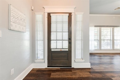 Entryway featuring wood finished floors, baseboards, and ornamental molding