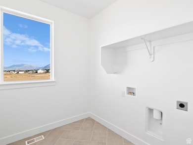 Washroom with a mountain view, washer hookup, hookup for an electric dryer, and light tile patterned floors