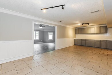 Empty room featuring wainscoting, track lighting, a textured ceiling, light tile patterned floors, and ornamental molding