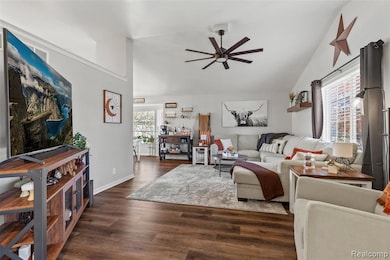 Living room featuring dark wood-style floors, a ceiling fan, and high vaulted ceiling