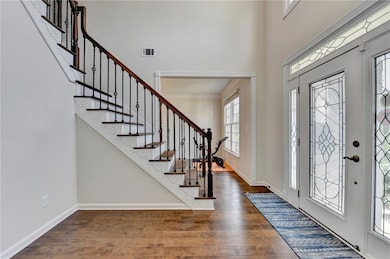 Entrance foyer featuring wood finished floors, a towering ceiling, and stairs