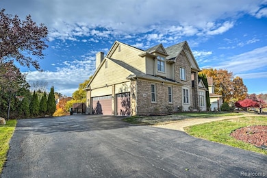 View of side of property featuring asphalt driveway, brick siding, a garage, a chimney, and a lawn