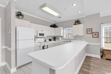 Kitchen with light countertops, a sink, a peninsul