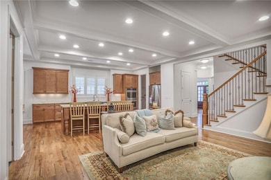 Living area featuring light wood-style floors, stairs, recessed lighting, beamed ceiling, and crown molding