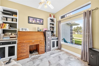 Office with a ceiling fan and light marble finish