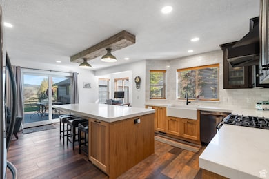 Kitchen featuring a kitchen island, a textured ceiling, backsplash, dark wood-style flooring, and brown cabinetry