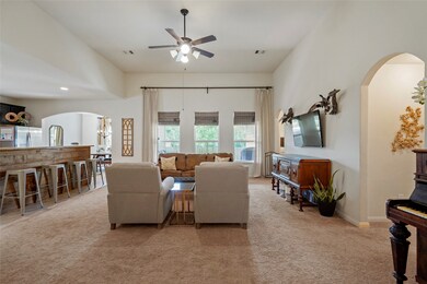 Heading into the home is an extremely spacious living room. Custom drapes which emphasize the height of the ceiling will stay. All this space lends itself to many furniture arrangements. This shot shows the hall to one of the secondary bedrooms to the right, the breakfast bar to the left and the dining room in the far left corner.