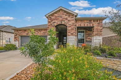 View of front of home featuring brick siding, driveway, an attached garage, and covered porch