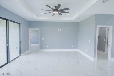 Unfurnished bedroom with a raised ceiling, access to exterior, light marble finish floors, a ceiling fan, and recessed lighting