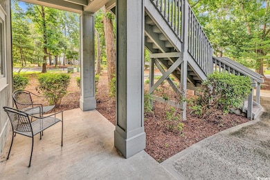 View of front porch featuring stairs and view of wooded area
