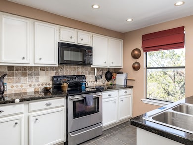 Kitchen with tasteful backsplash, black microwave