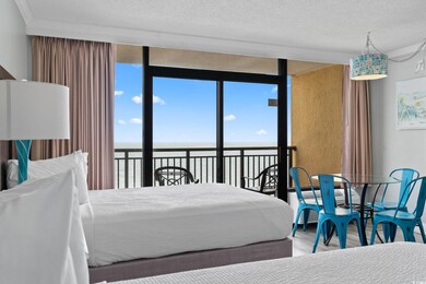 Bedroom featuring wood finished floors, multiple windows, a water view, a textured ceiling, and a wall of windows