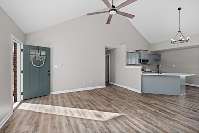 Entrance foyer with high vaulted ceiling, dark wood-type flooring, a chandelier, and a ceiling fan