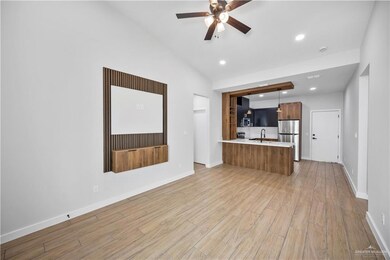 Unfurnished living room with light wood-type flooring, baseboards, a sink, and ceiling fan