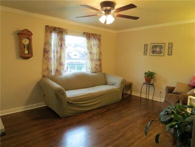 THE BRIGHT AND OPEN LIVING ROOM FEATURES GLEAMING HARDWOOD FLOORS, CROWN MOLDING, AND A CEILING FAN.