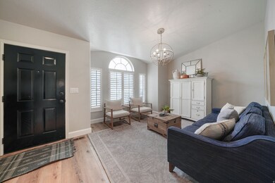 Living room with light wood-type flooring, vaulted ceiling, and a chandelier