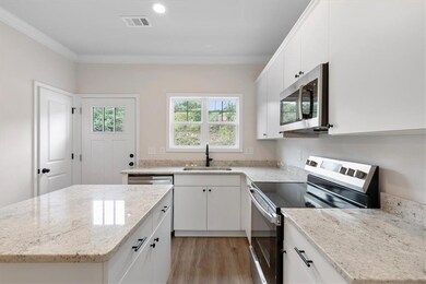 Kitchen with sink, white cabinetry, light hardwood