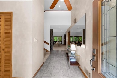 Foyer with stairway, a ceiling fan, a high ceiling
