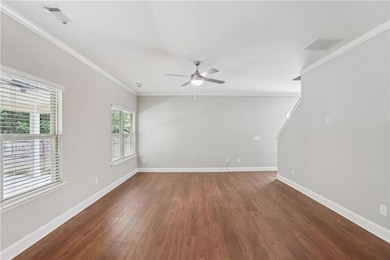 Unfurnished room featuring crown molding, ceiling fan, baseboards, and wood finished floors