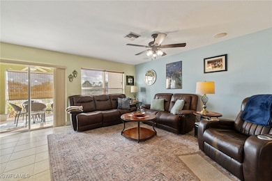 Living room with ceiling fan and light tile patter