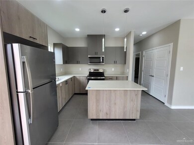 Kitchen with appliances with stainless steel finishes, light tile patterned floors, light countertops, modern cabinets, and a kitchen island