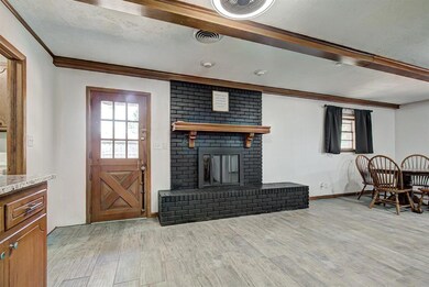 Living room with a brick fireplace, light wood-type flooring, and crown molding