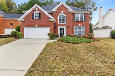 View of front of house with brick siding, a front lawn, and driveway