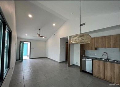 Kitchen featuring high vaulted ceiling, stainless steel dishwasher, a sink, brown cabinetry, and visible vents
