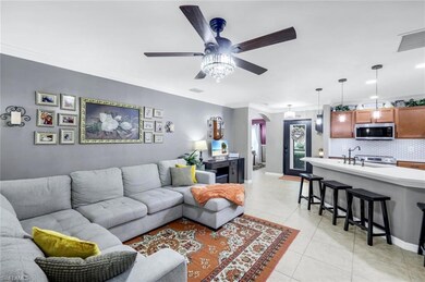 Living area with ornamental molding, arched walkways, light tile patterned floors, ceiling fan, and recessed lighting