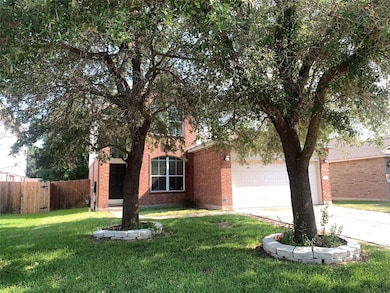 View of property hidden behind natural elements featuring driveway and brick siding