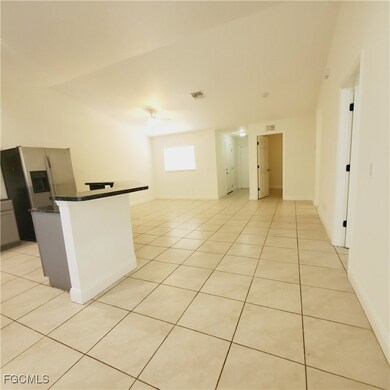 Kitchen with dark countertops, light tile patterned floors, stainless steel fridge with ice dispenser, a kitchen island, and gray cabinetry