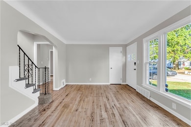 Foyer featuring light wood-style floors, arched walkways, and stairs