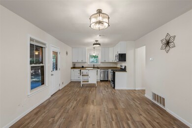 Kitchen featuring appliances with stainless steel finishes, white cabinetry, dark wood-type flooring, a chandelier, and wooden counters