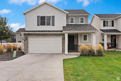 View of front of home featuring stone siding, a garage, a front yard, driveway, and a porch