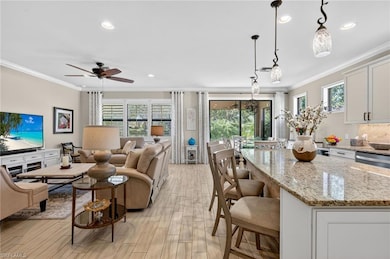 Kitchen featuring crown molding, a breakfast bar, light stone counters, open floor plan, and recessed lighting