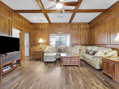 Living room with coffered ceiling and dark wood-type flooring
