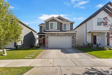 View of front of house with concrete driveway, a front lawn, an attached garage, and stone siding