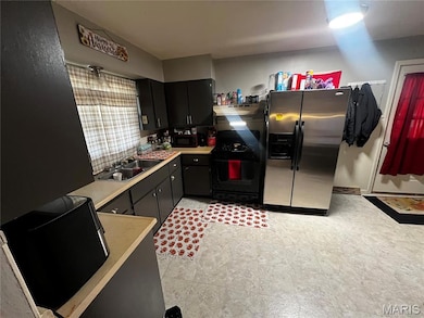 Kitchen with black appliances, light countertops, under cabinet range hood, and dark cabinetry