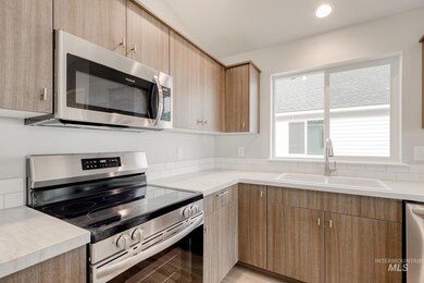 Kitchen featuring stainless steel appliances, light countertops, and modern cabinets