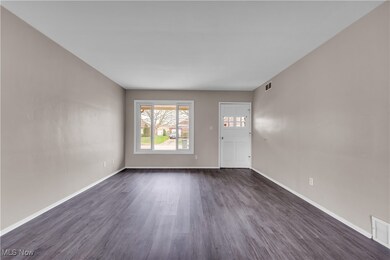 Unfurnished living room featuring dark wood-type flooring and baseboards