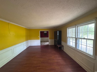 Spare room with a textured ceiling, wainscoting, w