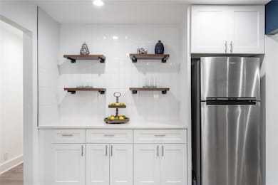 Kitchen with open shelves, freestanding refrigerator, and backsplash